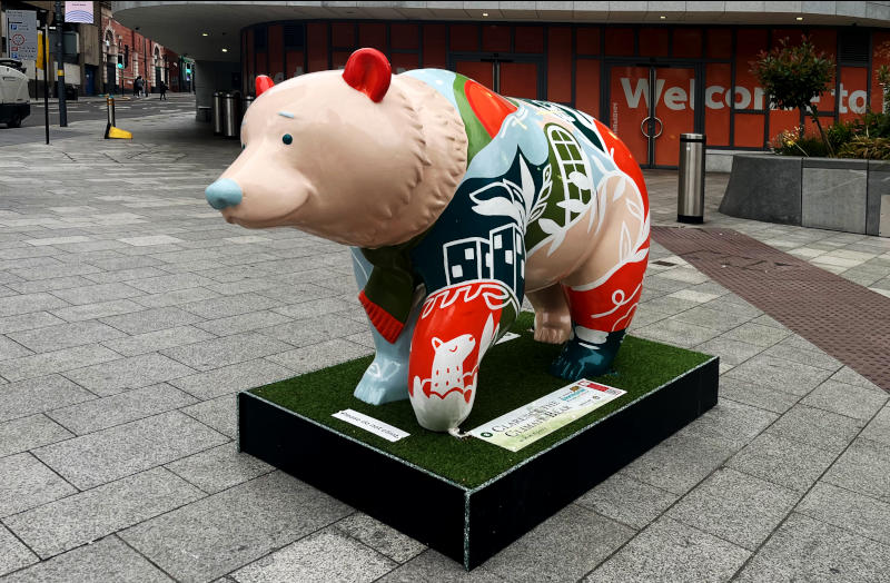 A large model bear mounted in a plinth, labelled Clarence the Climate Bear, on the pavement outside one corner of New Street Station