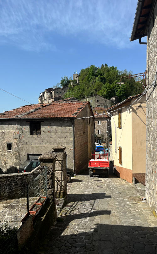 A small truck goes along a narrow street between two buildings