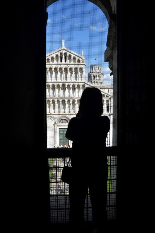 Silhouette of a woman, viewed through an arch, taking a photo of the Cathedral