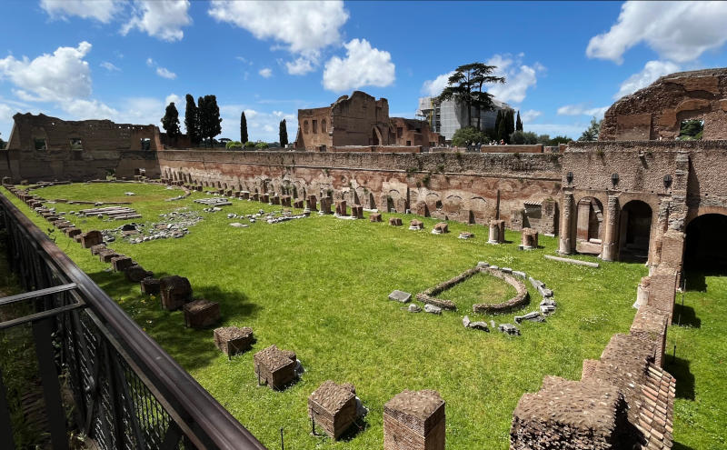 A long grassed area, enclosed by walls, with the remains of a colonnade inside the walls