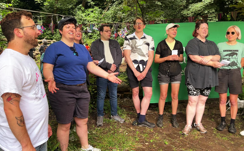 A group of singers outdoors singing with no printed music or words, from memory