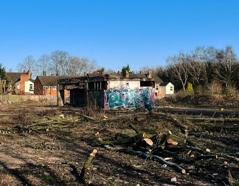 A derelict concrete building (containing and electricity substation) in the middle of waste ground